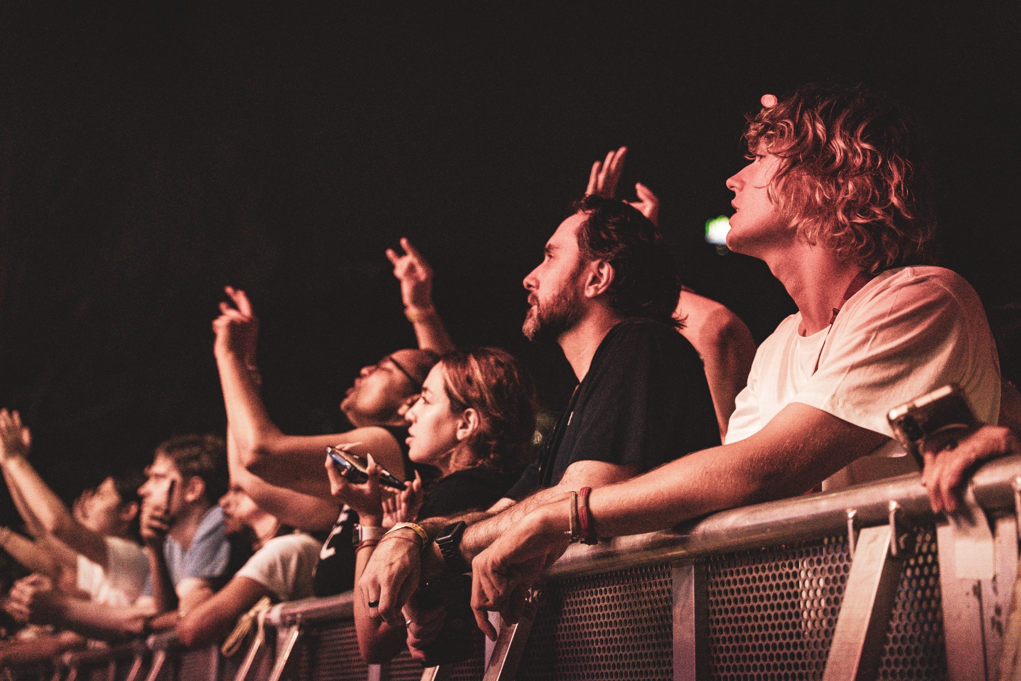 A line of punters standing against the stage barrier.