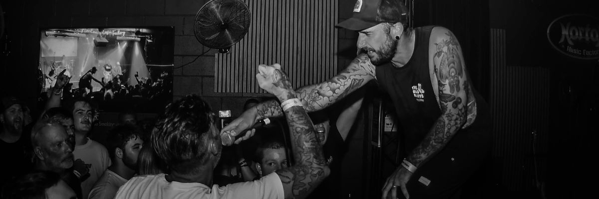 Photo of Fake News passing a mic to a punter from the stage at Norton Music Factory.