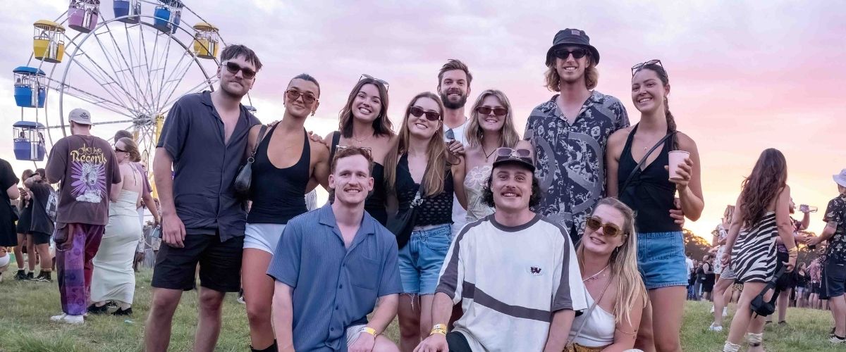 Friends posing at Big Pineapple Festival with a ferris wheel in the background