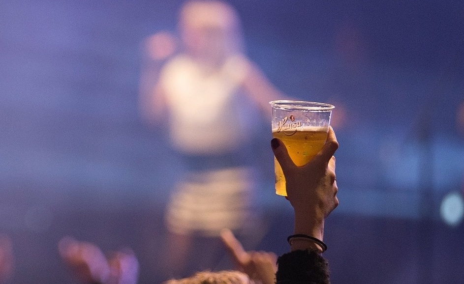 Photo of a punter raising a beer in the air towards the stage.