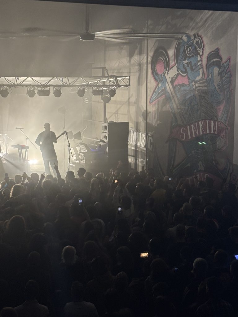 A moody scene where a band is playing to the crowd at Blackflag Brewing