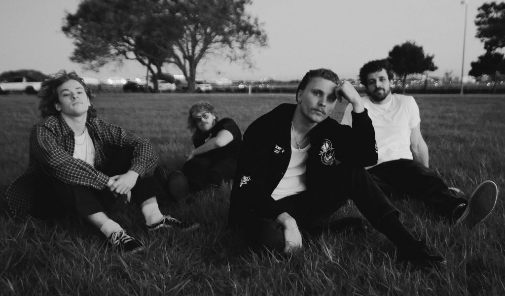 Che Burns with his band sitting in a grassy park