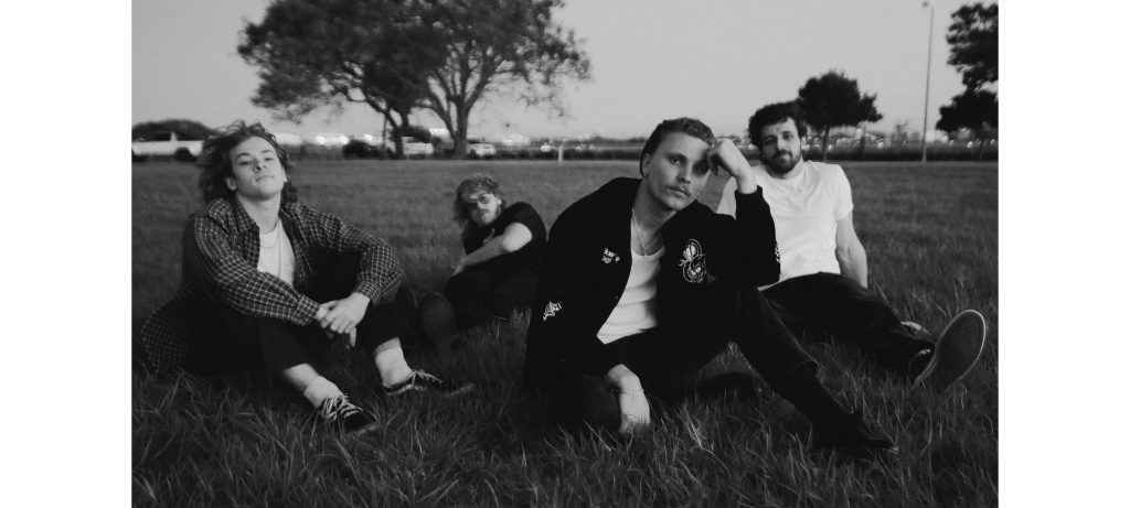 Che Burns with his band sitting in a grassy park